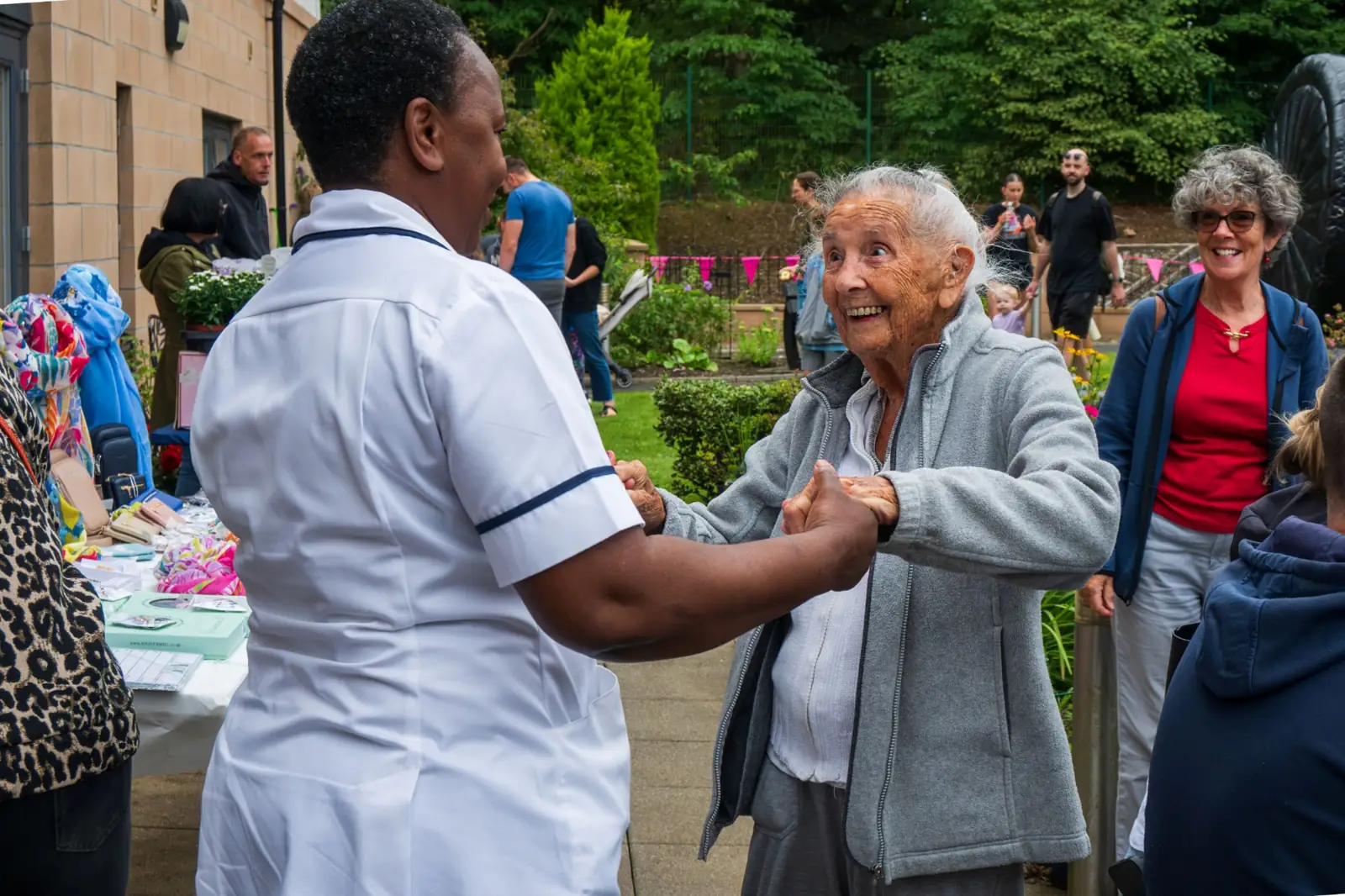 A resident dancing with a nurse in the garden at Mearns House Care Home during the summer fete