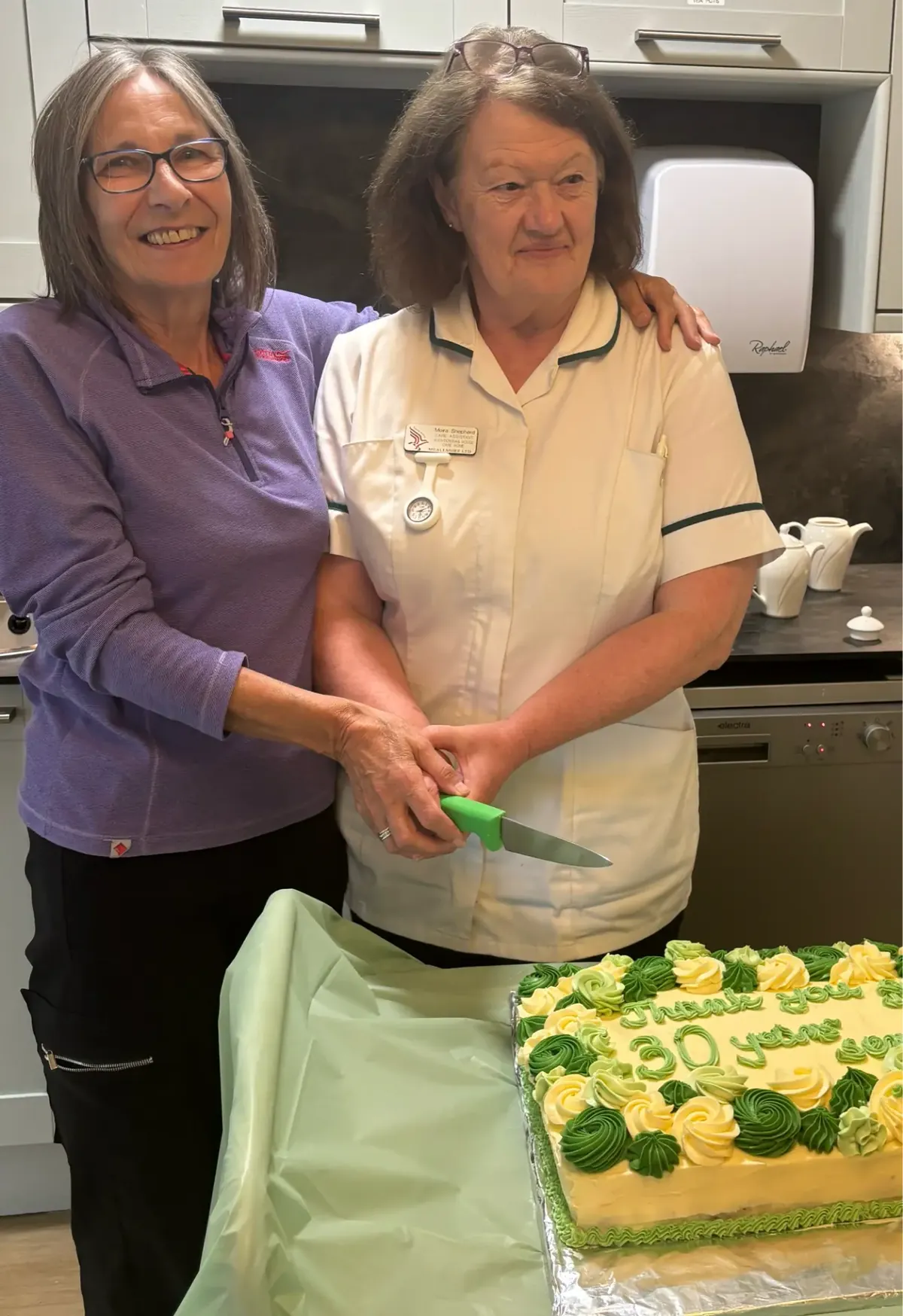 Elaine Shepherd and Moira Shepherd cutting a celebration cake marking 30 years of service at Auchtercrag House Care Home