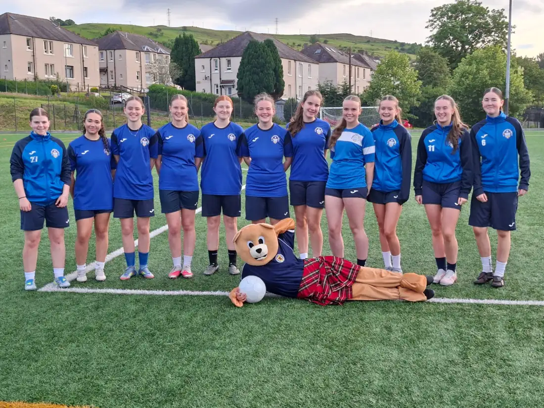 Greenock Morton u16s regional football team lined up on the pitch with Roary the mascot after supporting Kincaid House Care Home