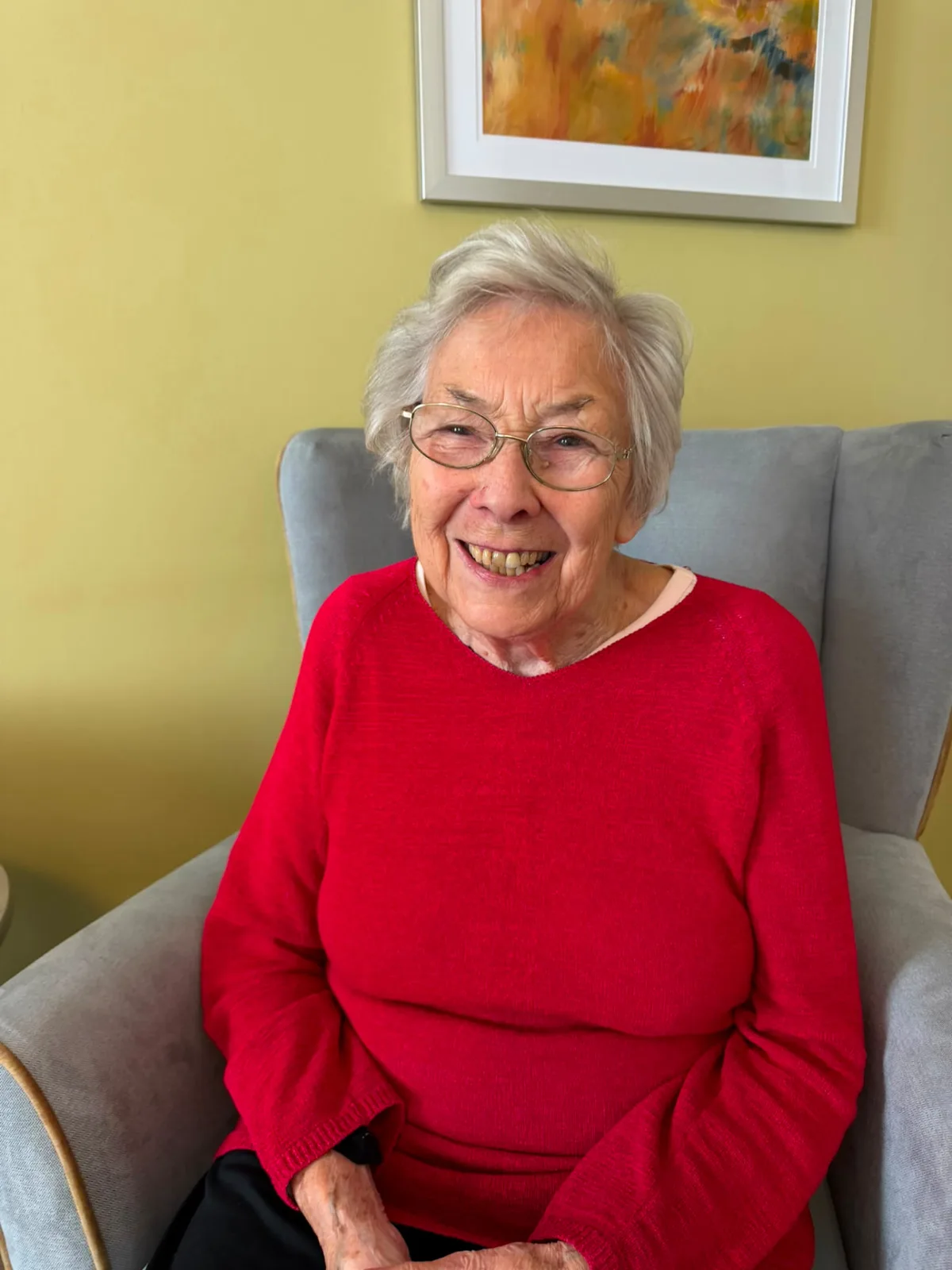 Moira Ord MBE, resident at Kelvinside Manor Care Home in Glasgow, smiling in her chair