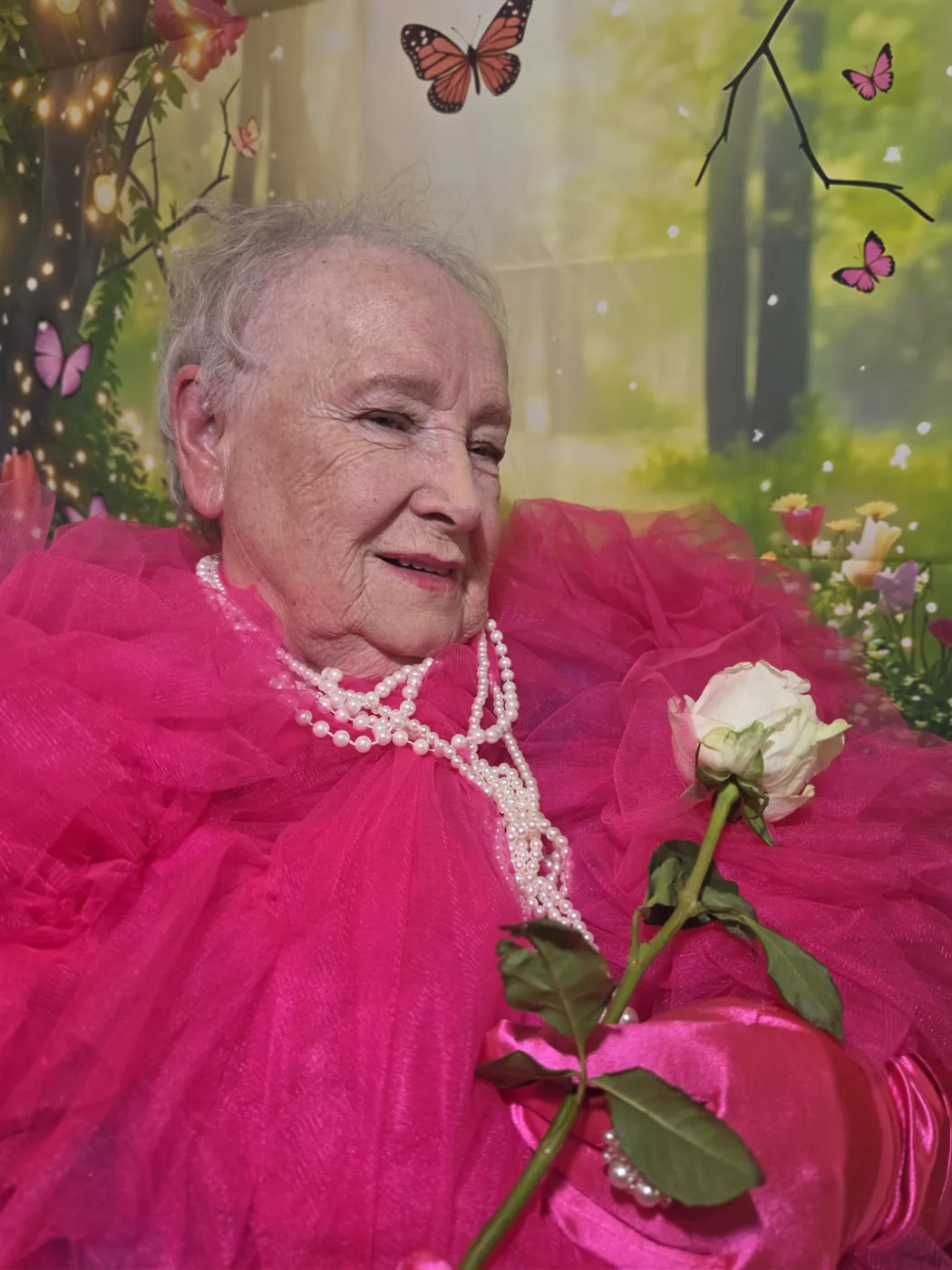 A resident at Parklands Care Home in Alloa holding a white rose and wearing pearls and a pink gown