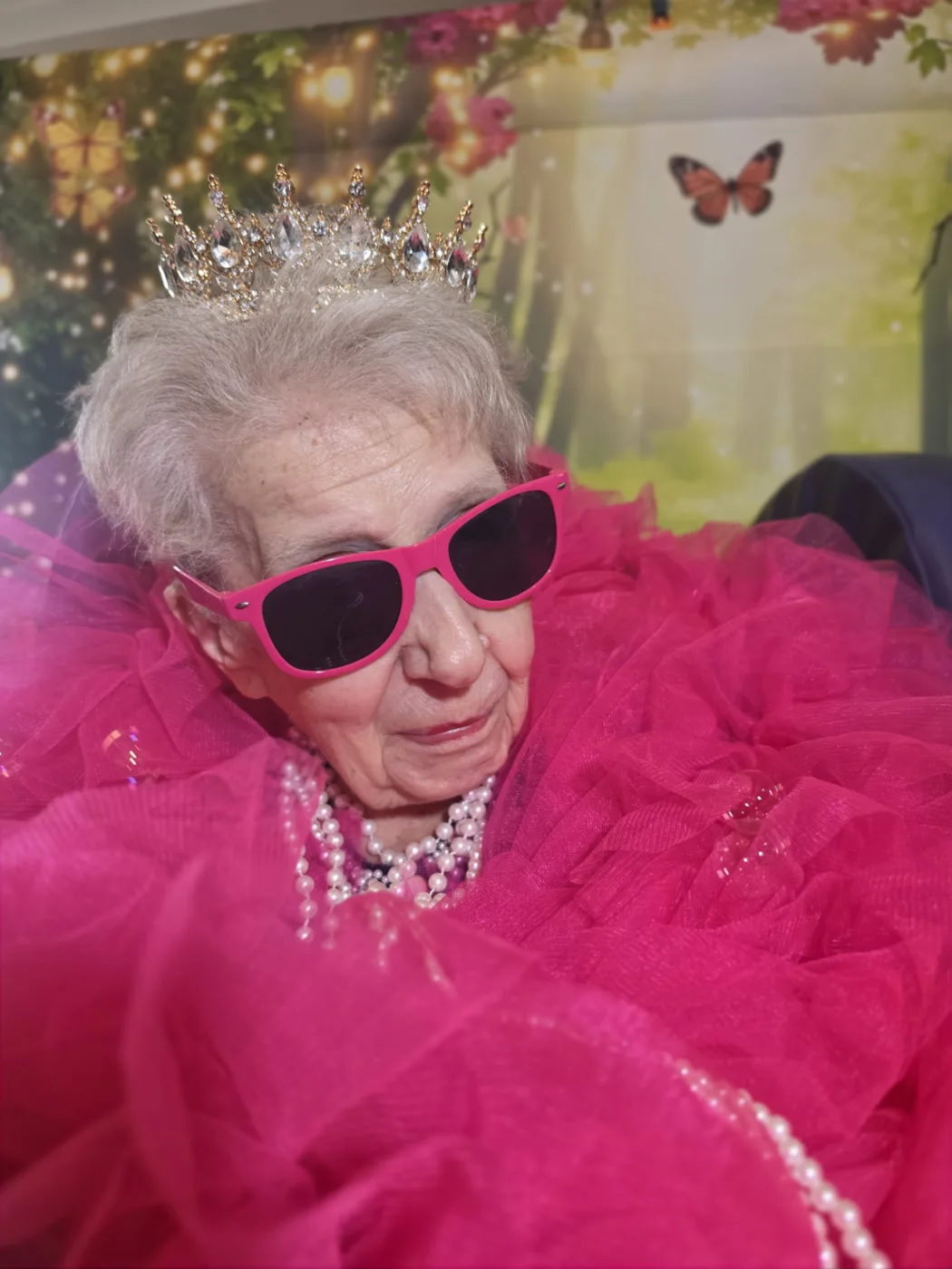 A resident at Parklands Care Home wearing a crown, pink sunglasses and pearls during the Queen for the Day photoshoot