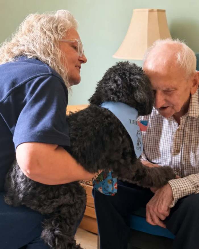 A resident stroking a visiting dog with a colleague at St Modans Care Home in Fraserburgh