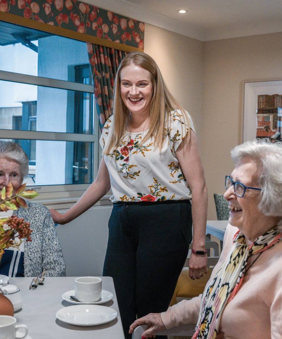 Meallmore residents laughing in the lounge at Kelvinside Manor with their Home Manager